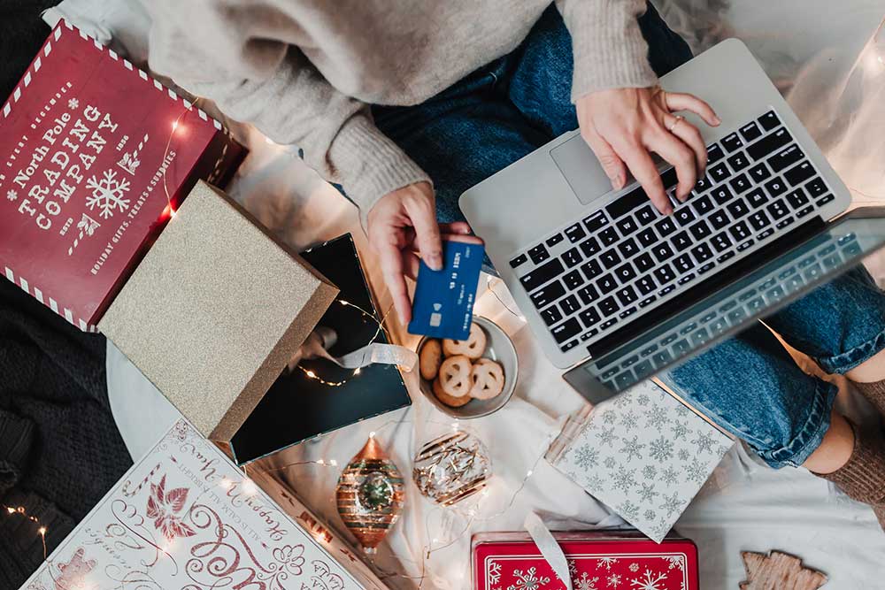 Woman shopping online surrounded by Christmas stuff